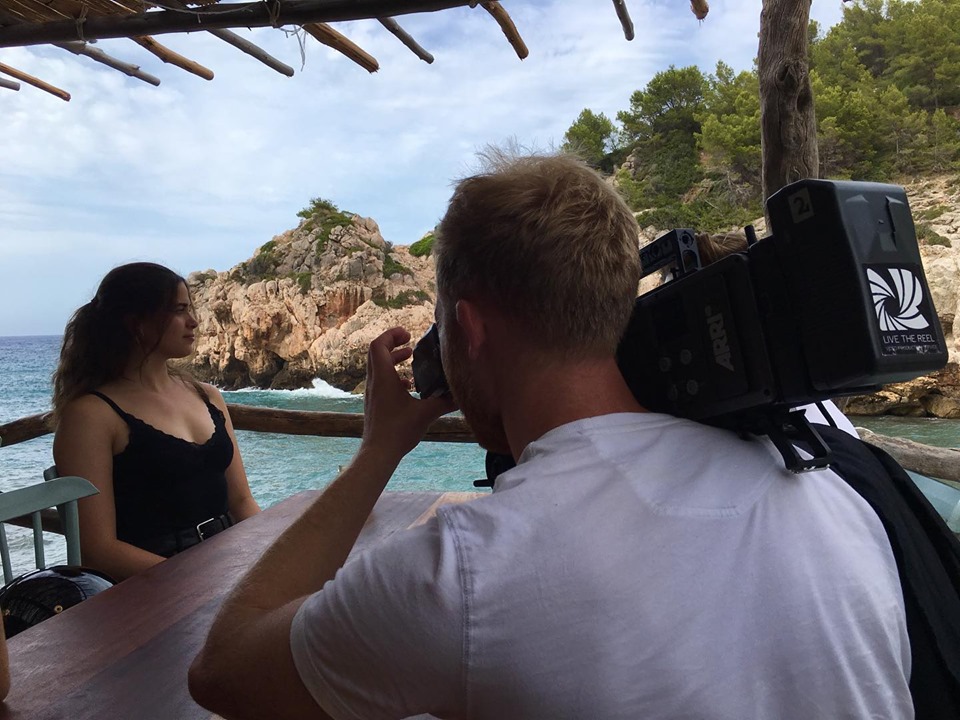 cameraman films woman sitting next to the sea for a travel film shot in Palma de Mallorca