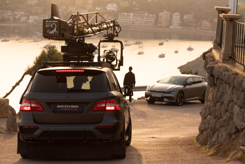 overlooking a sunrise in a mallorca bay a model stands as scorpio arm films him next to the picture car