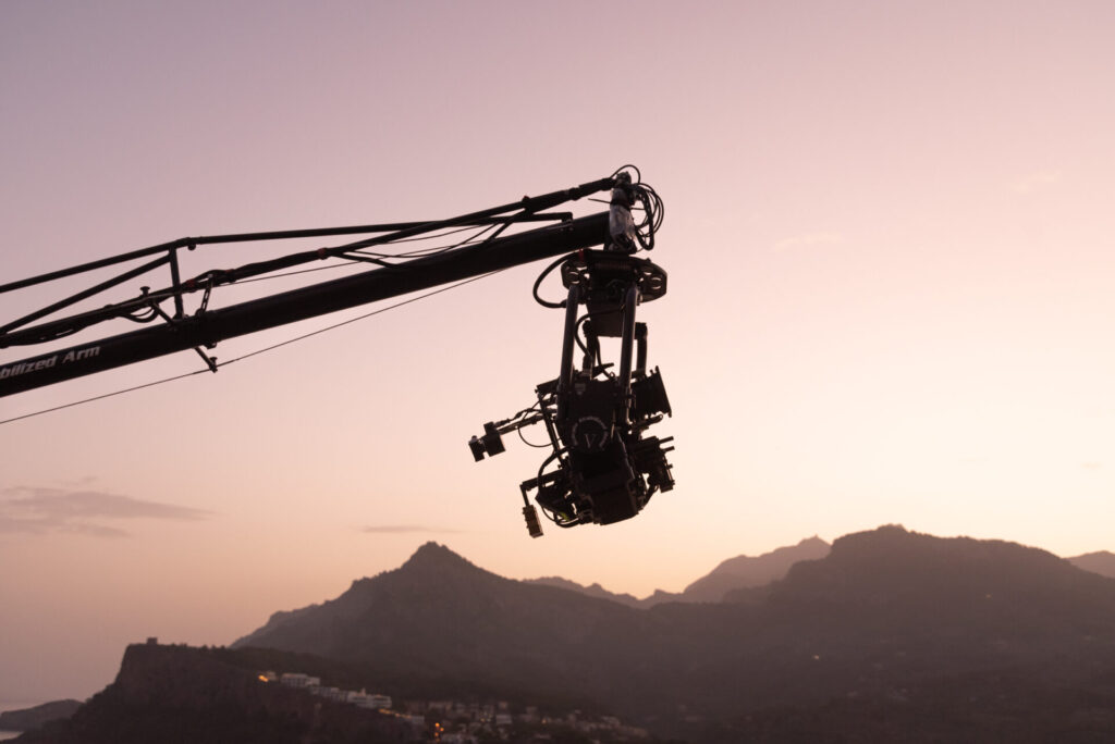 sunrise of a camera crane carrying an alexa mini lf with mountains in the background